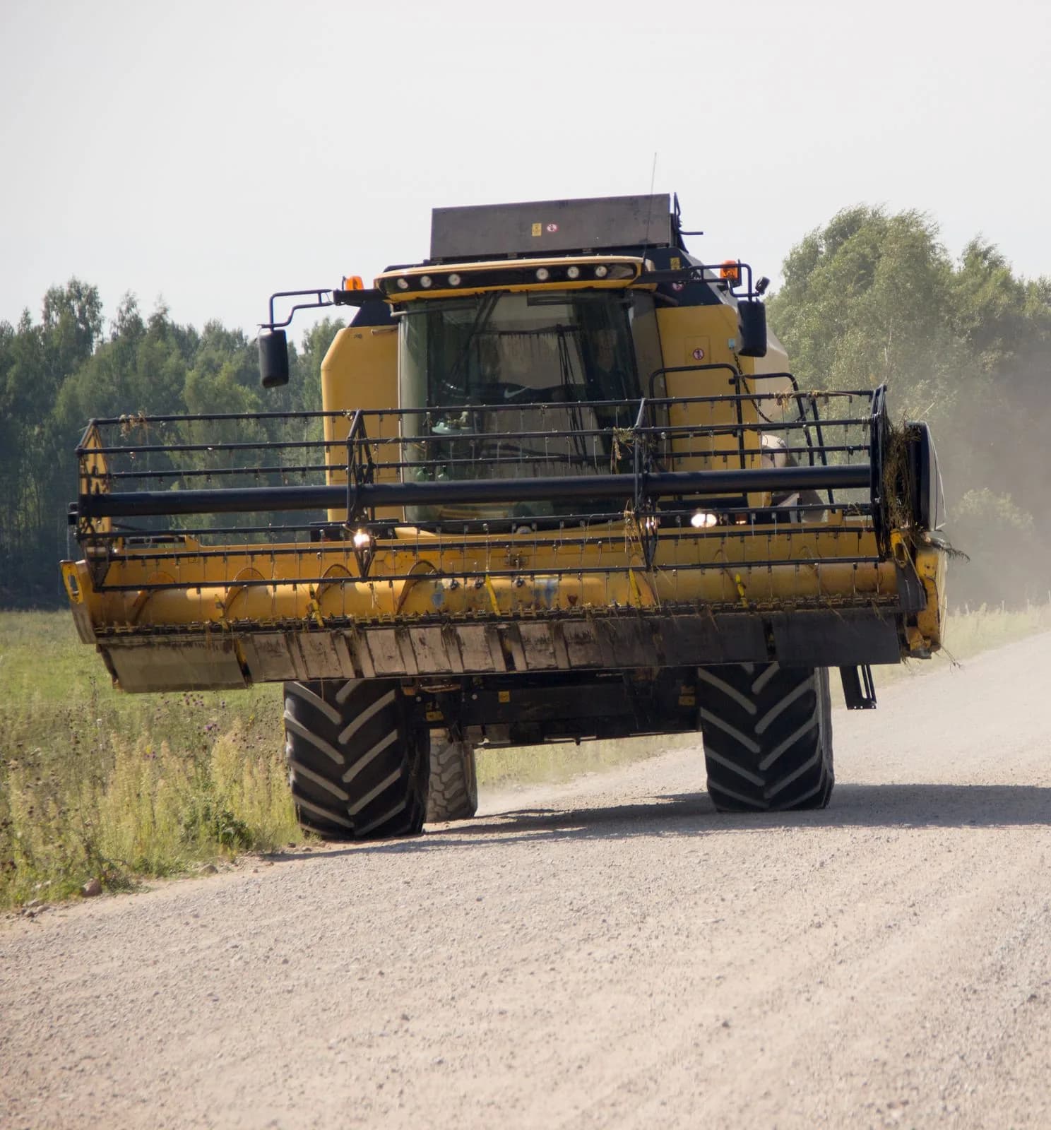 Combină agricolă deplasându-se pe un drum rural de pământ