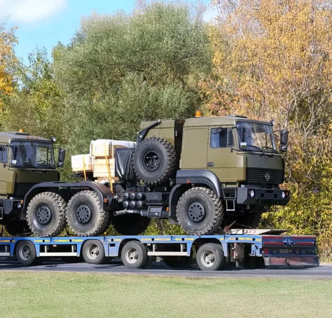 Camioane militare încărcate pe o semiremorcă cu platformă joasă